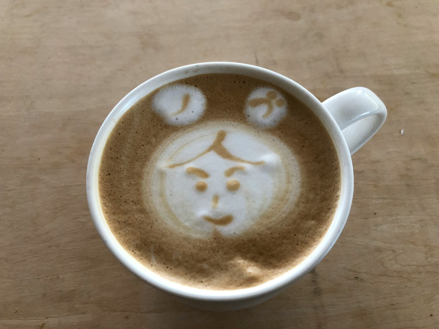 Latte art in a cup featuring a bear face design