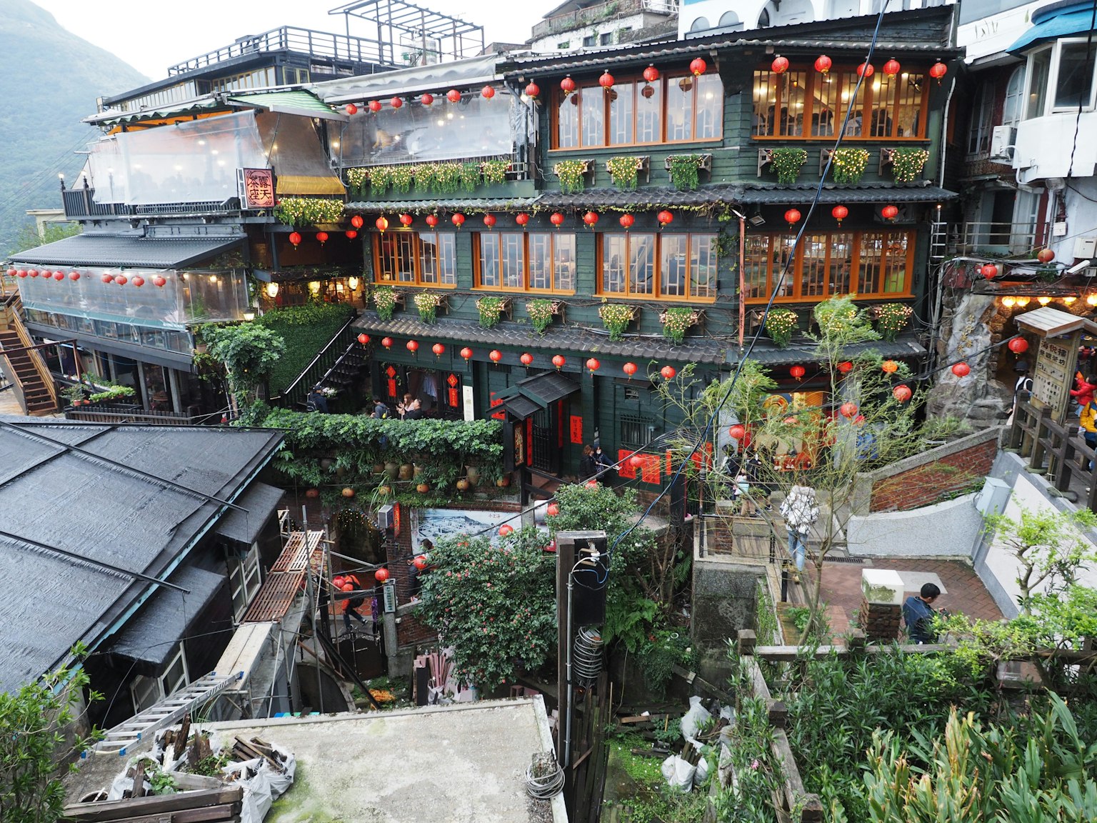 Edifici tradizionali taiwanesi immersi in un paesaggio montano con lanterne rosse e vegetazione lussureggiante