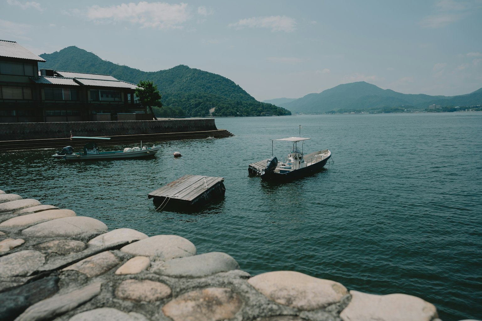 ทิวทัศน์ที่เงียบสงบพร้อมภูเขาและเรือเล็กใกล้ท่าเทียบเรือ