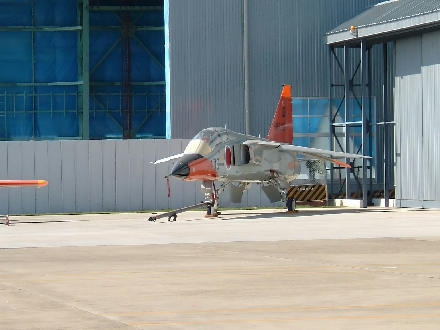 Un avion militaire garé à côté d'un hangar
