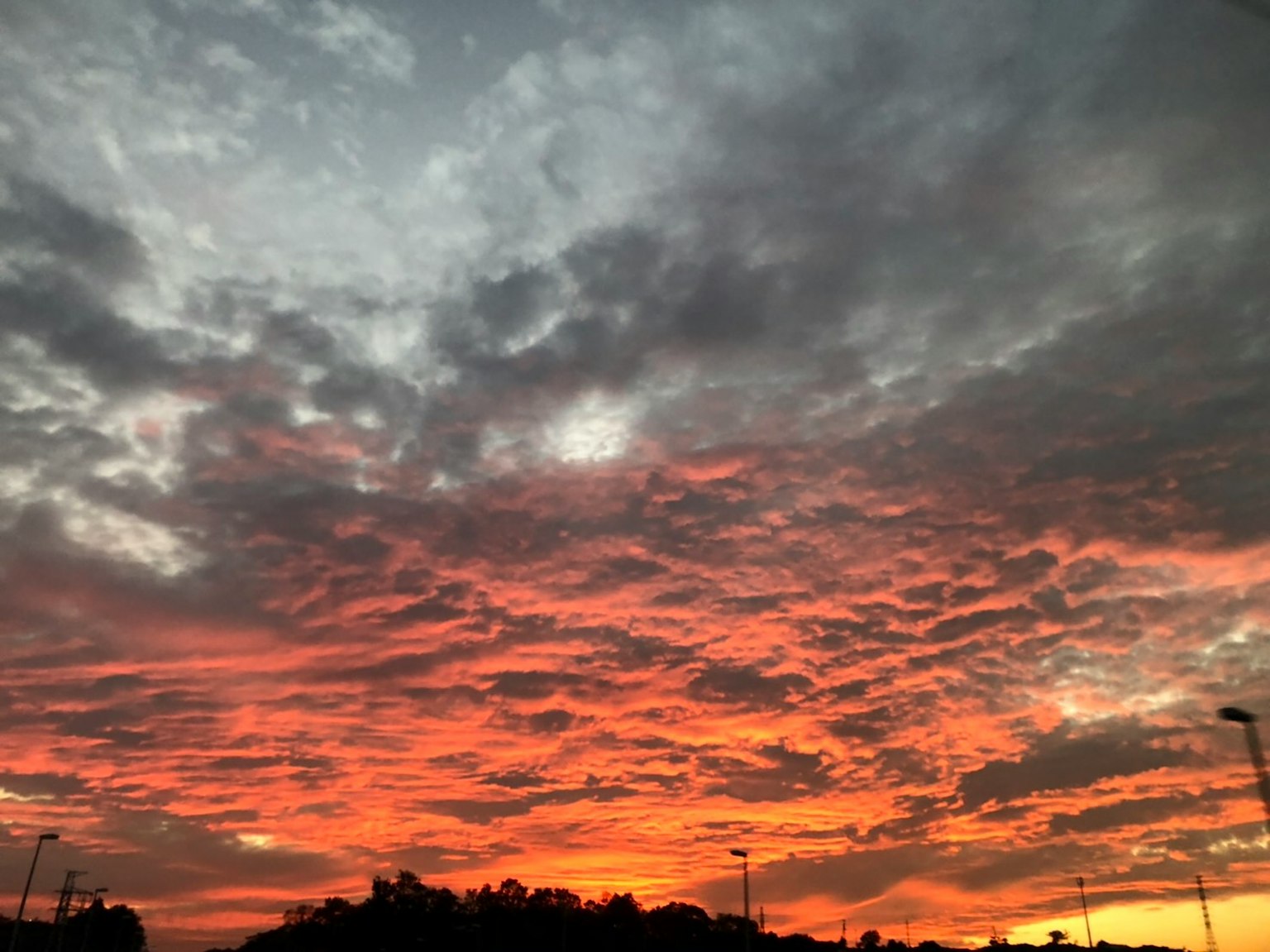 Senja dramatis dengan awan oranye dan abu-abu memenuhi langit