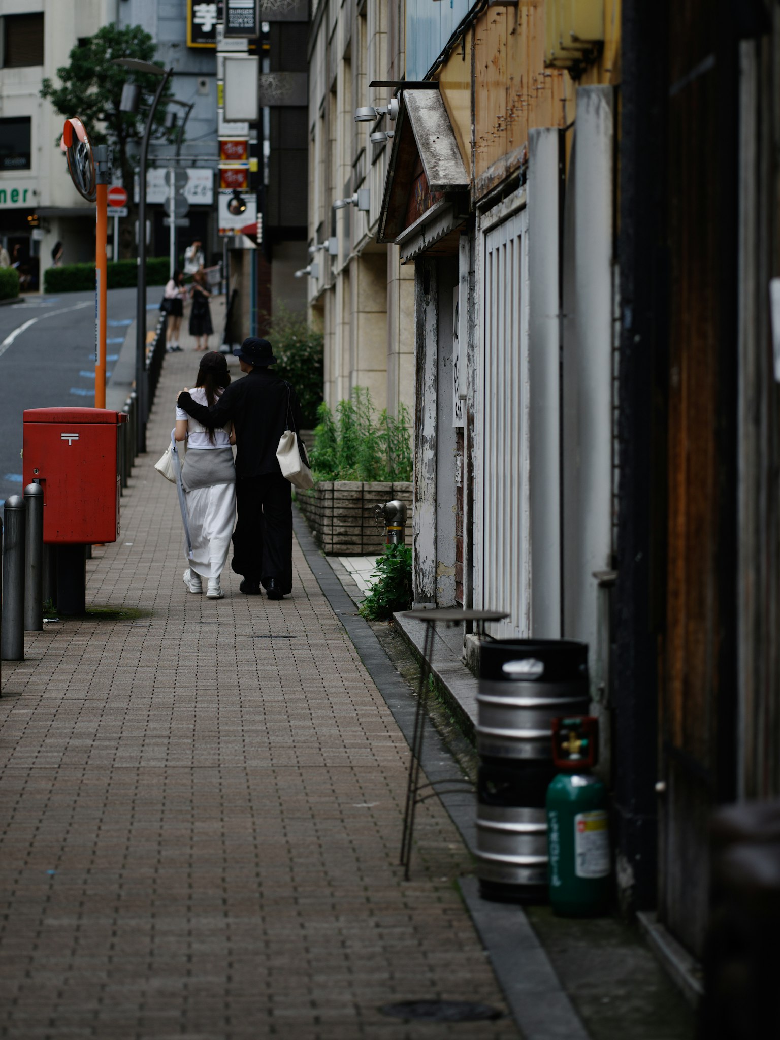 Una mujer en kimono blanco y un hombre en ropa negra caminando por una calle