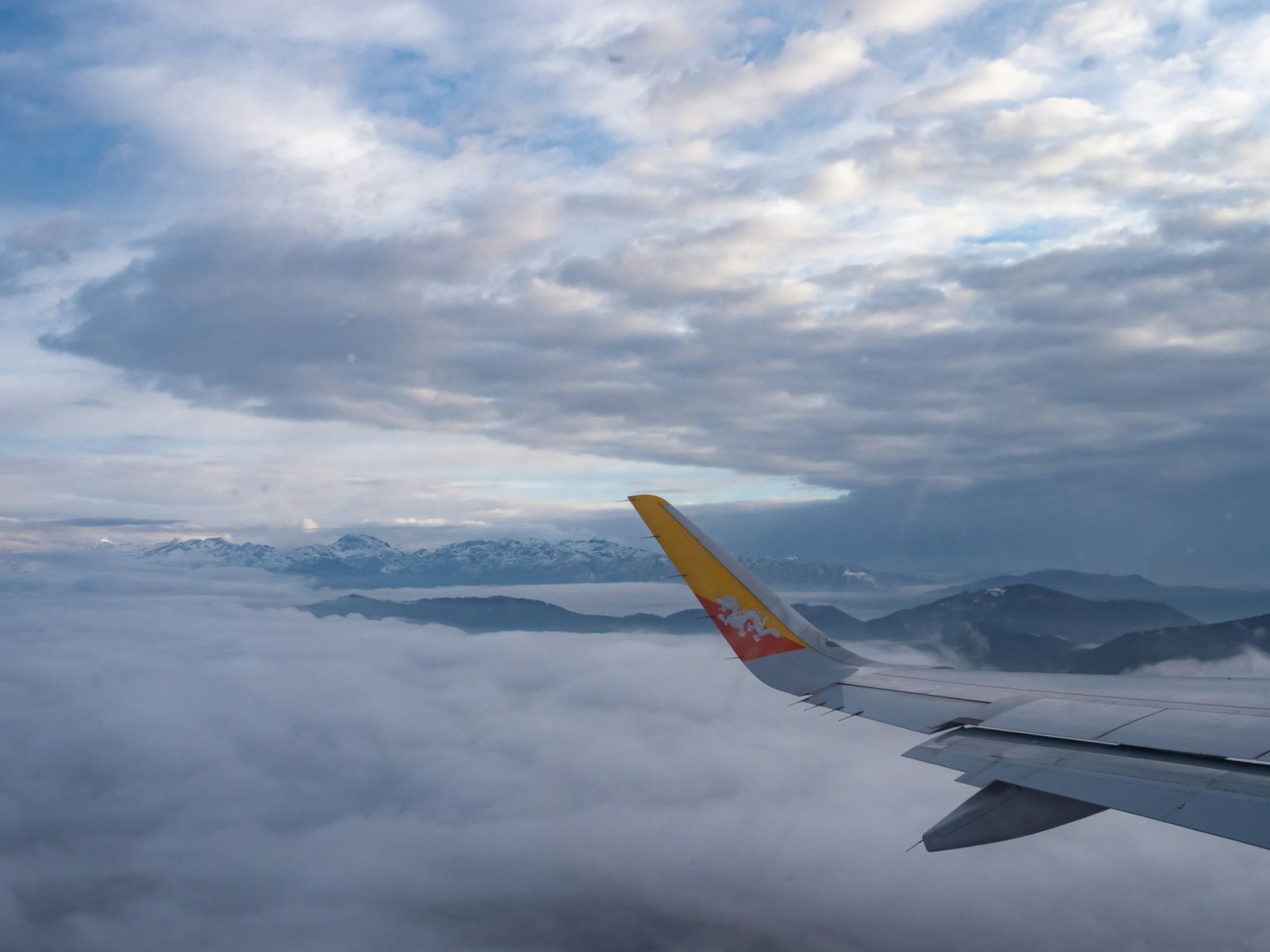 Flügel eines Flugzeugs über Wolken mit blauem Himmel und weißen Wolken