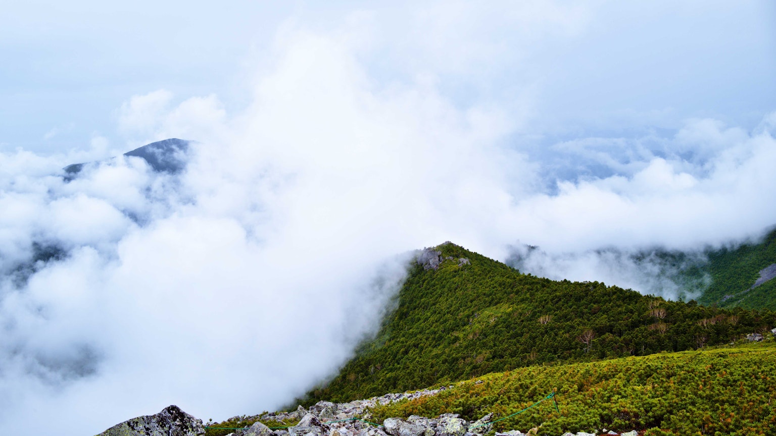 被雾笼罩的山景 绿色草地和白色云朵