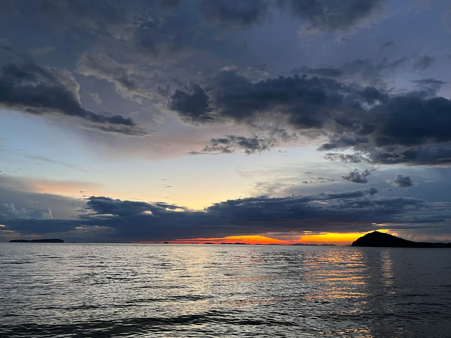 Mer tranquille avec des nuages sombres au coucher du soleil
