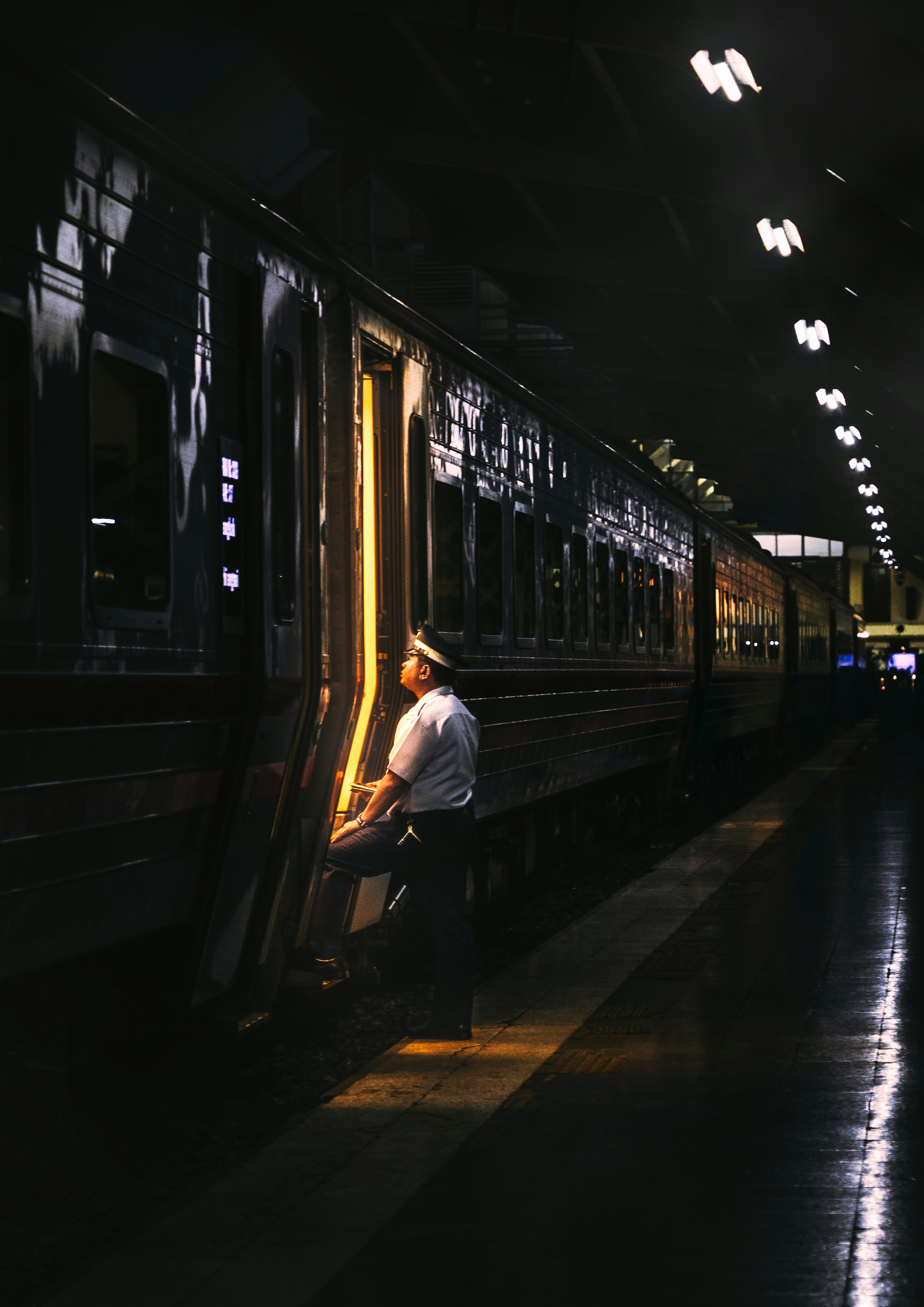 夜の駅ホームで列車の側面を見つめる人のシーン