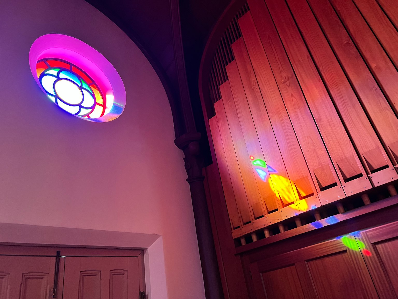 Interior gereja dengan kaca patri berwarna dan organ kayu