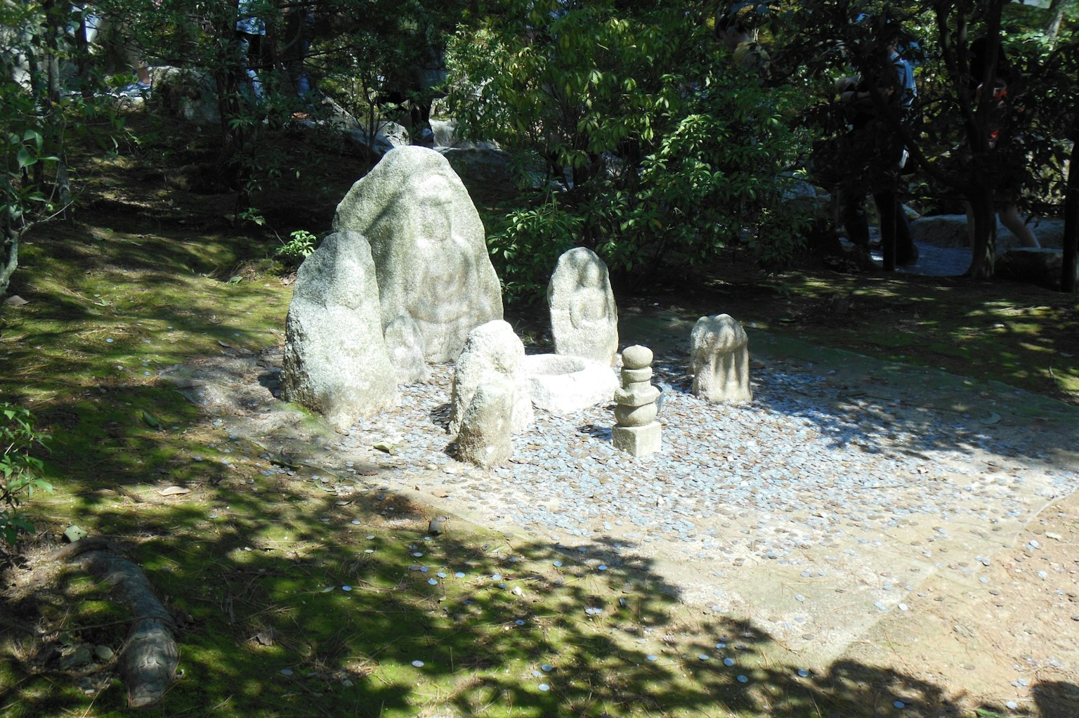 A serene park scene featuring stone sculptures surrounded by greenery