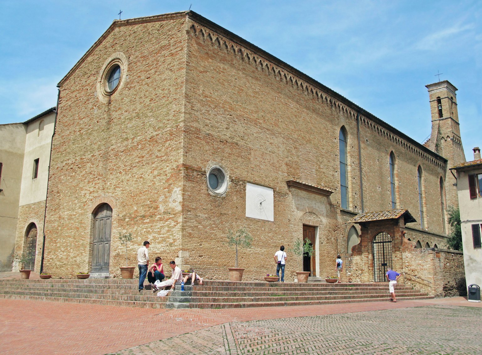 Esterno di una chiesa storica sotto un cielo blu con turisti nelle vicinanze
