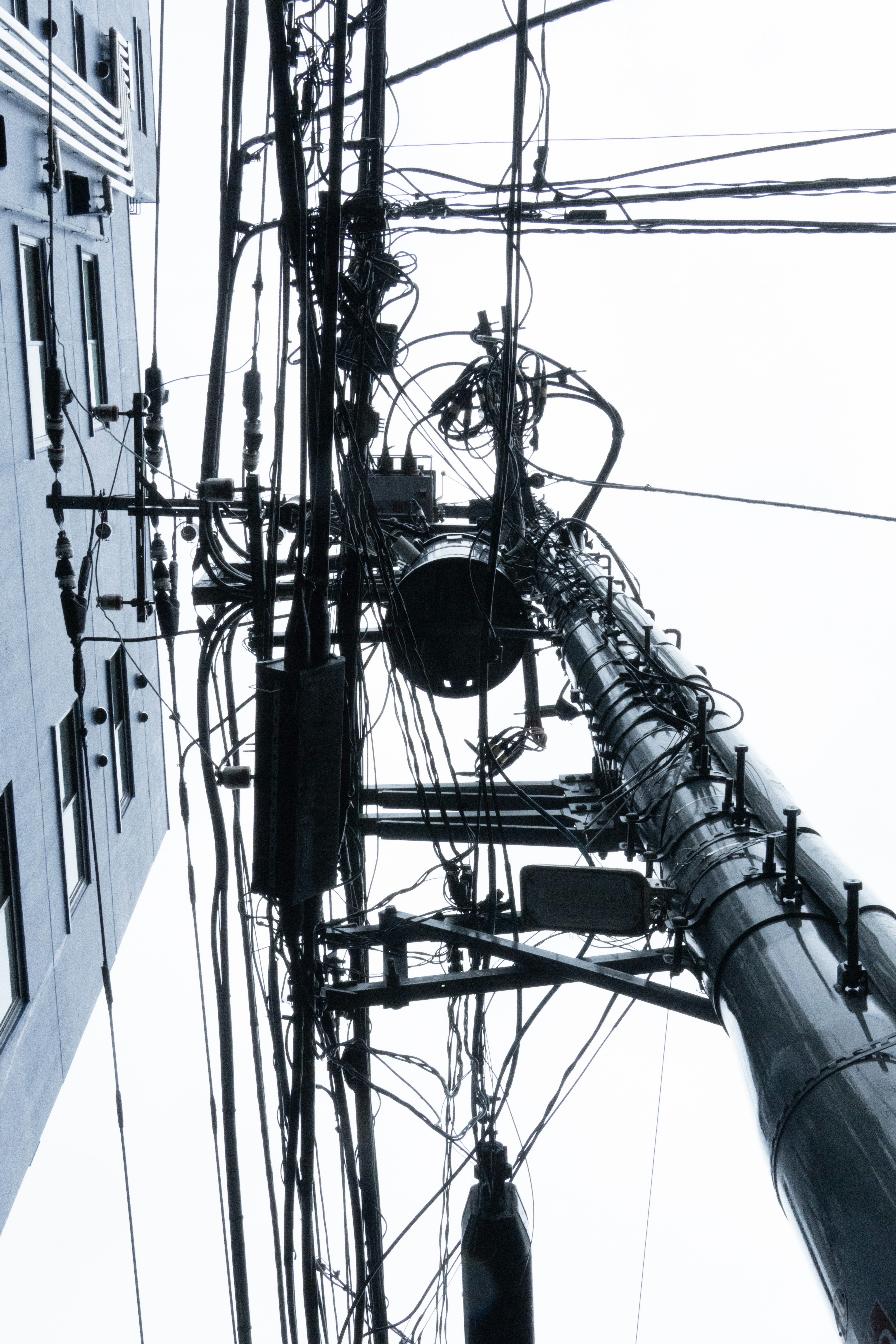 電線が絡み合う路地の空を見上げた眺め