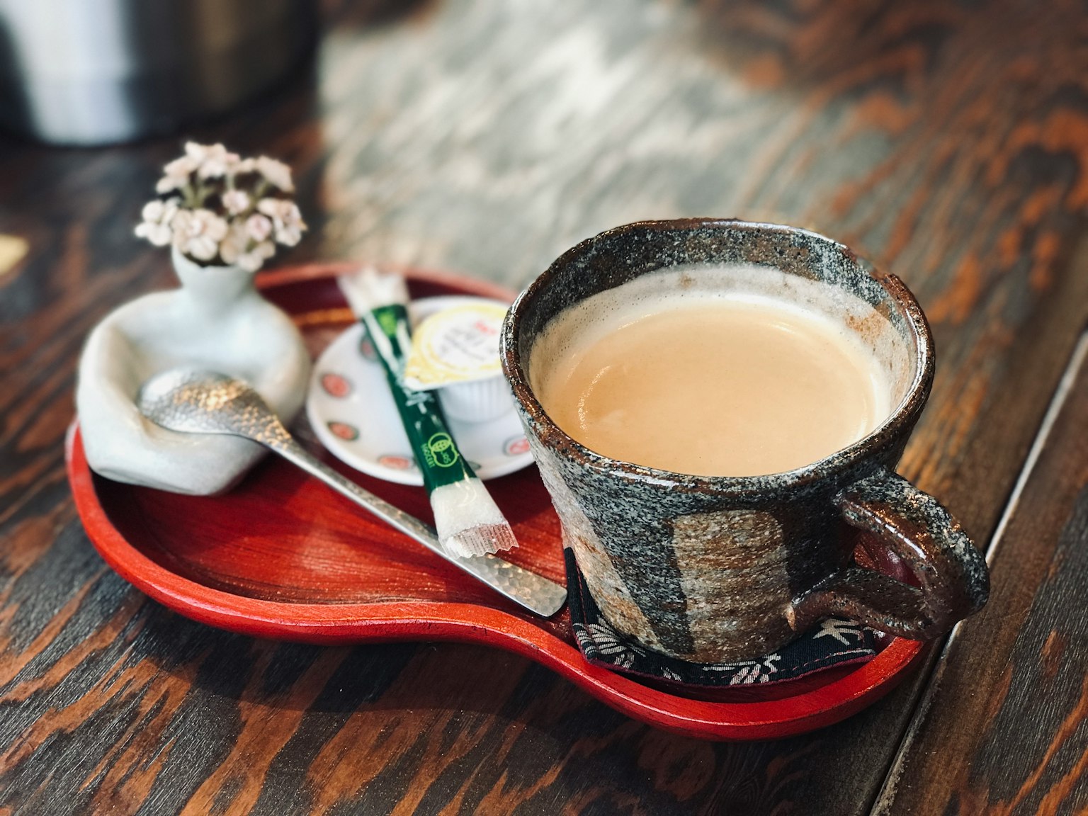 Ceramic cup of coffee with a small vase on a tray