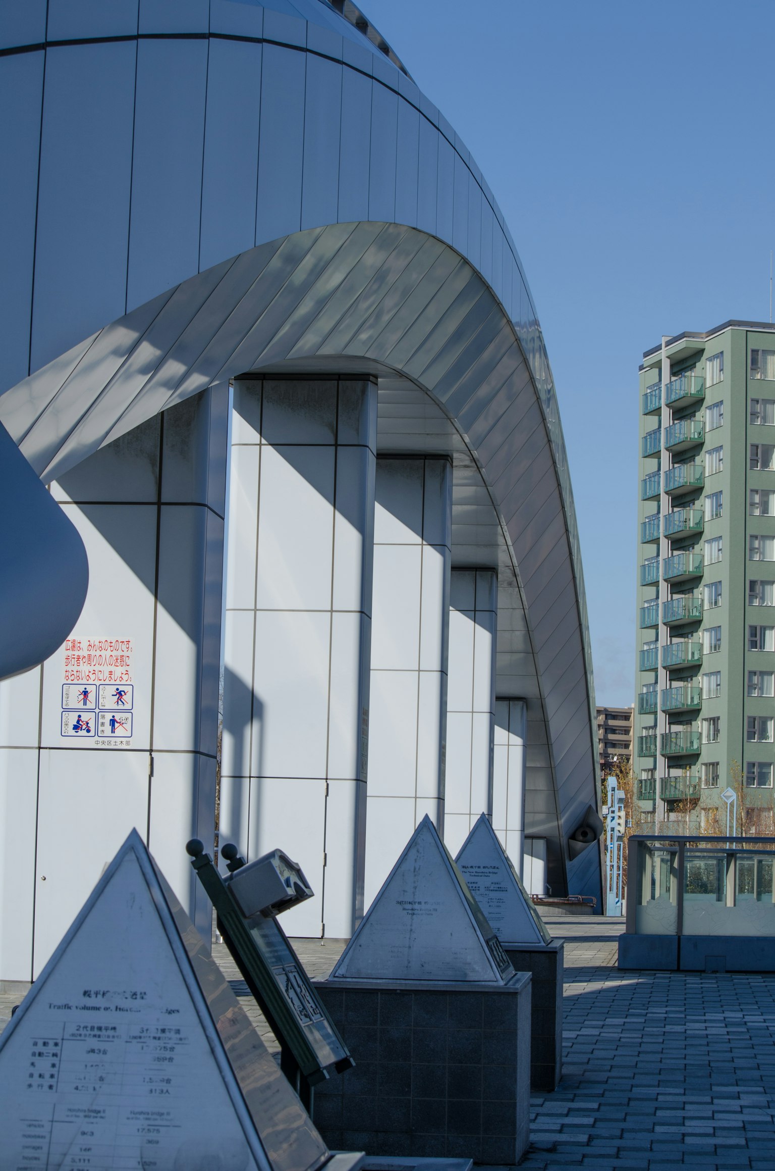 Moderne Gebäudeaußenansicht mit dreieckigen Skulpturen im Vordergrund