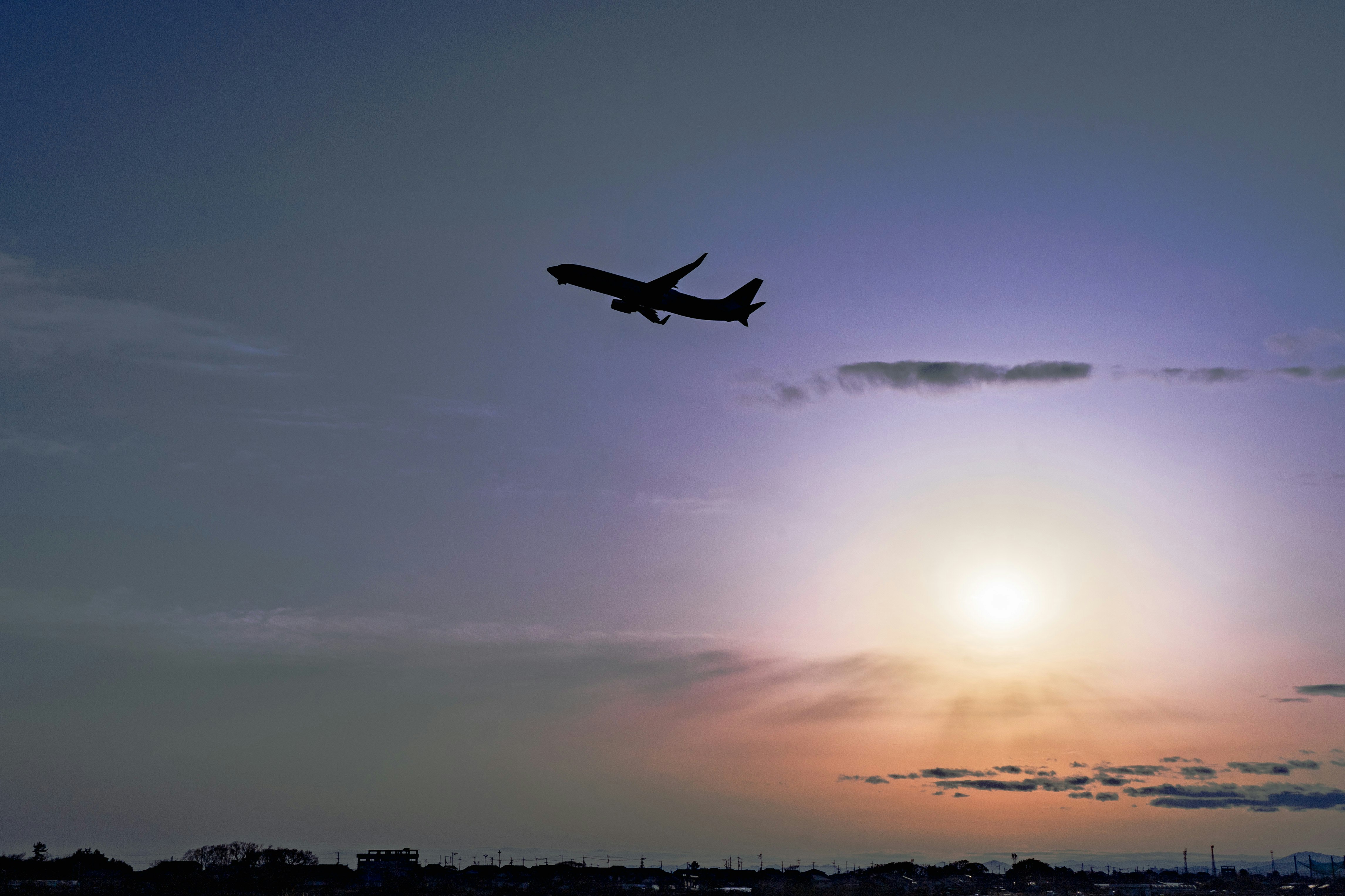 夕暮れの空を飛ぶ飛行機と雲の流れ