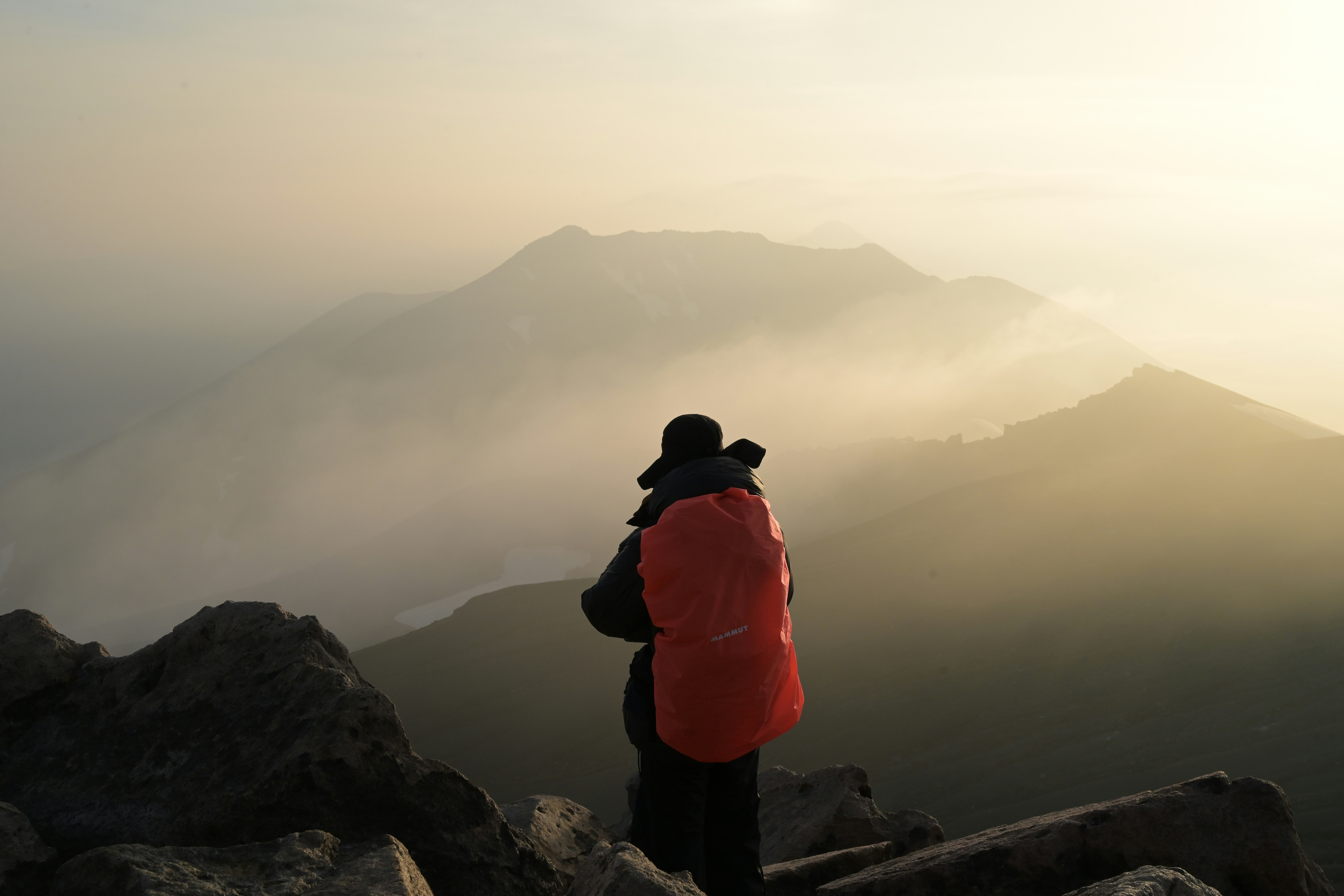 Silhouette eines Wanderers, der auf einem nebligen Berggrat entlanggeht