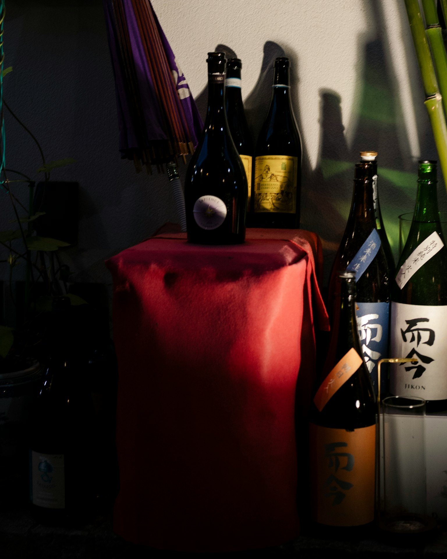 赤い布の上に置かれた日本酒の瓶が並ぶシーン