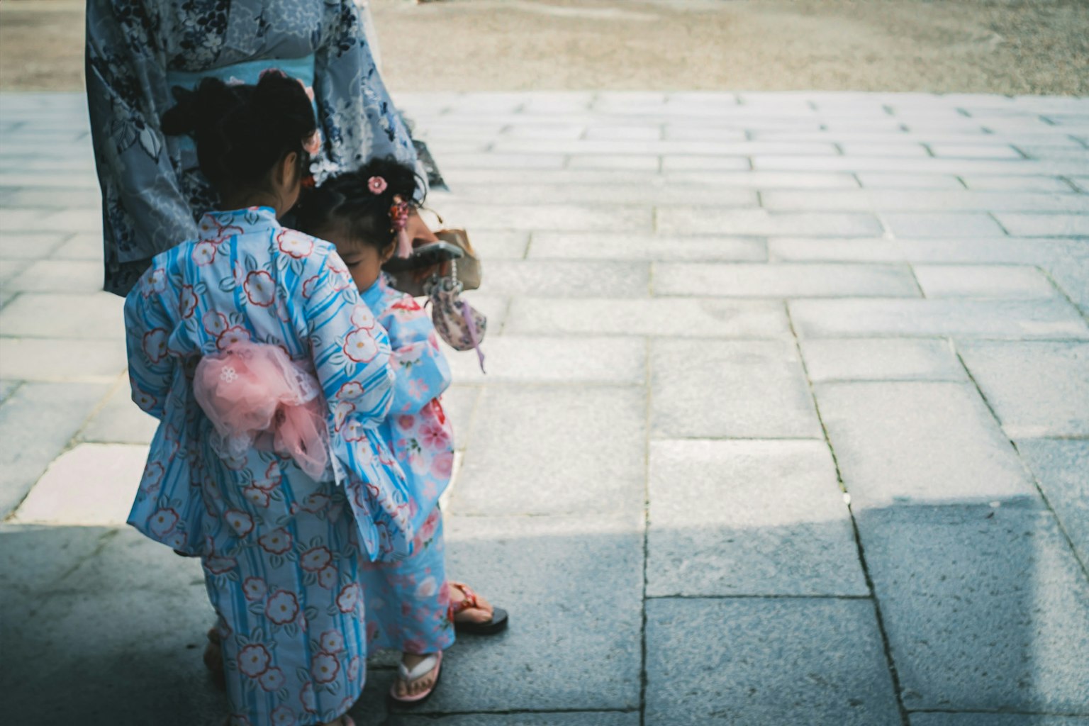 Trẻ em trong trang phục kimono truyền thống đứng trên nền đá