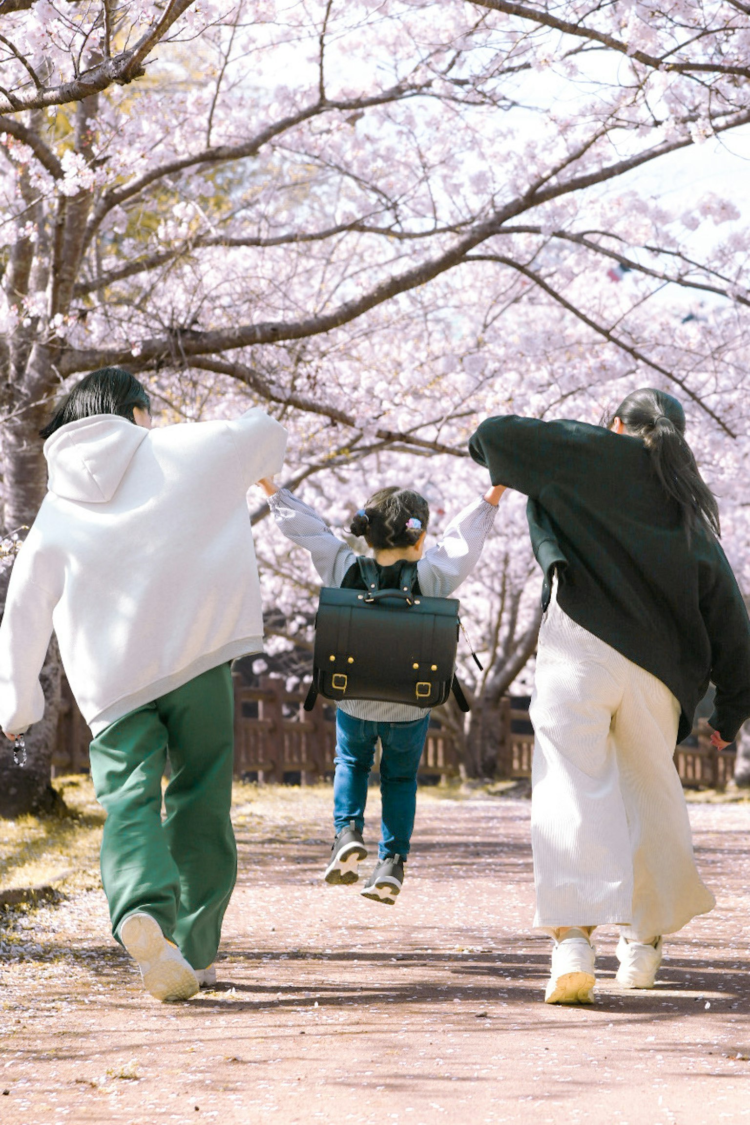 桜の木の下で遊ぶ子供たちの後ろ姿