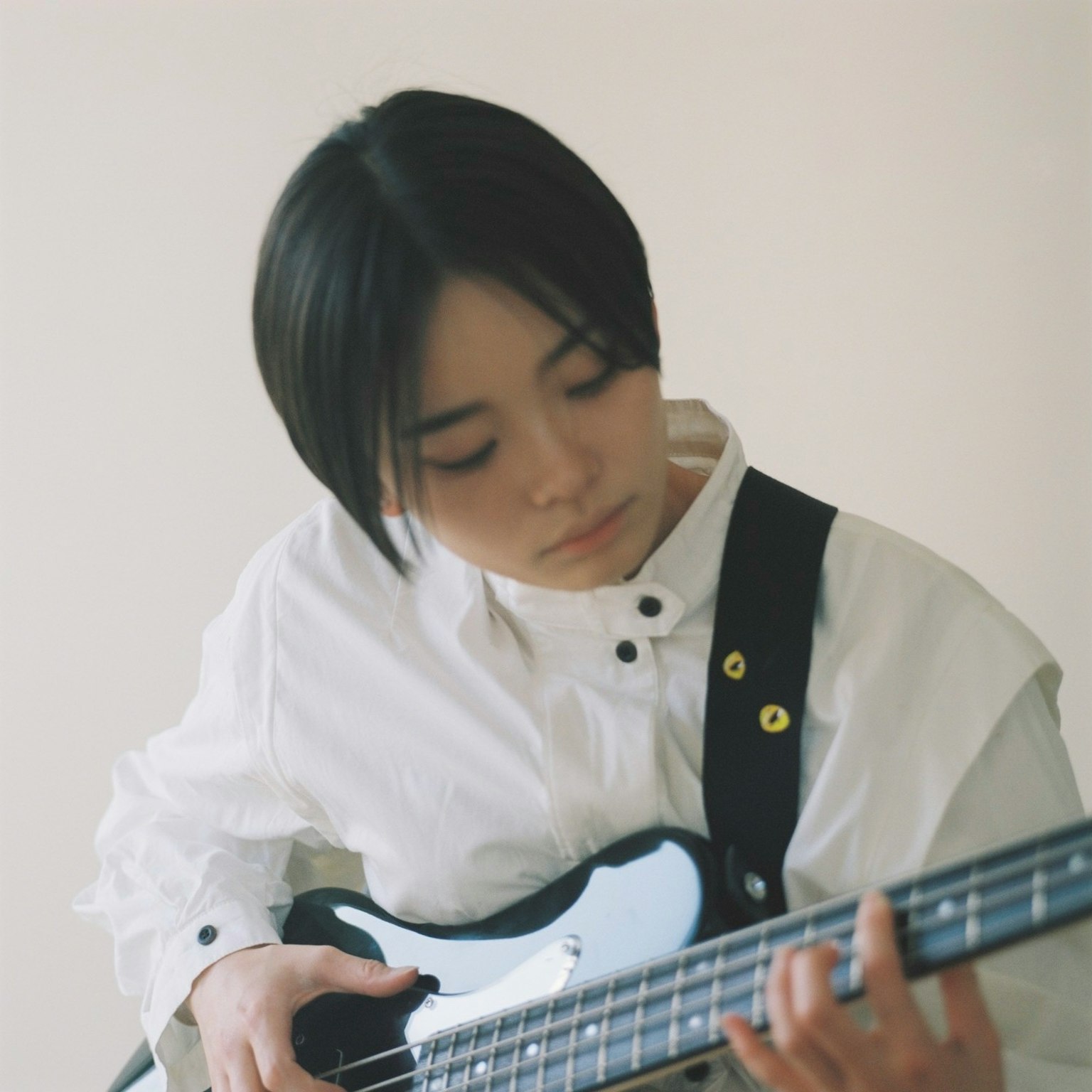 Una joven con camisa blanca tocando un bajo