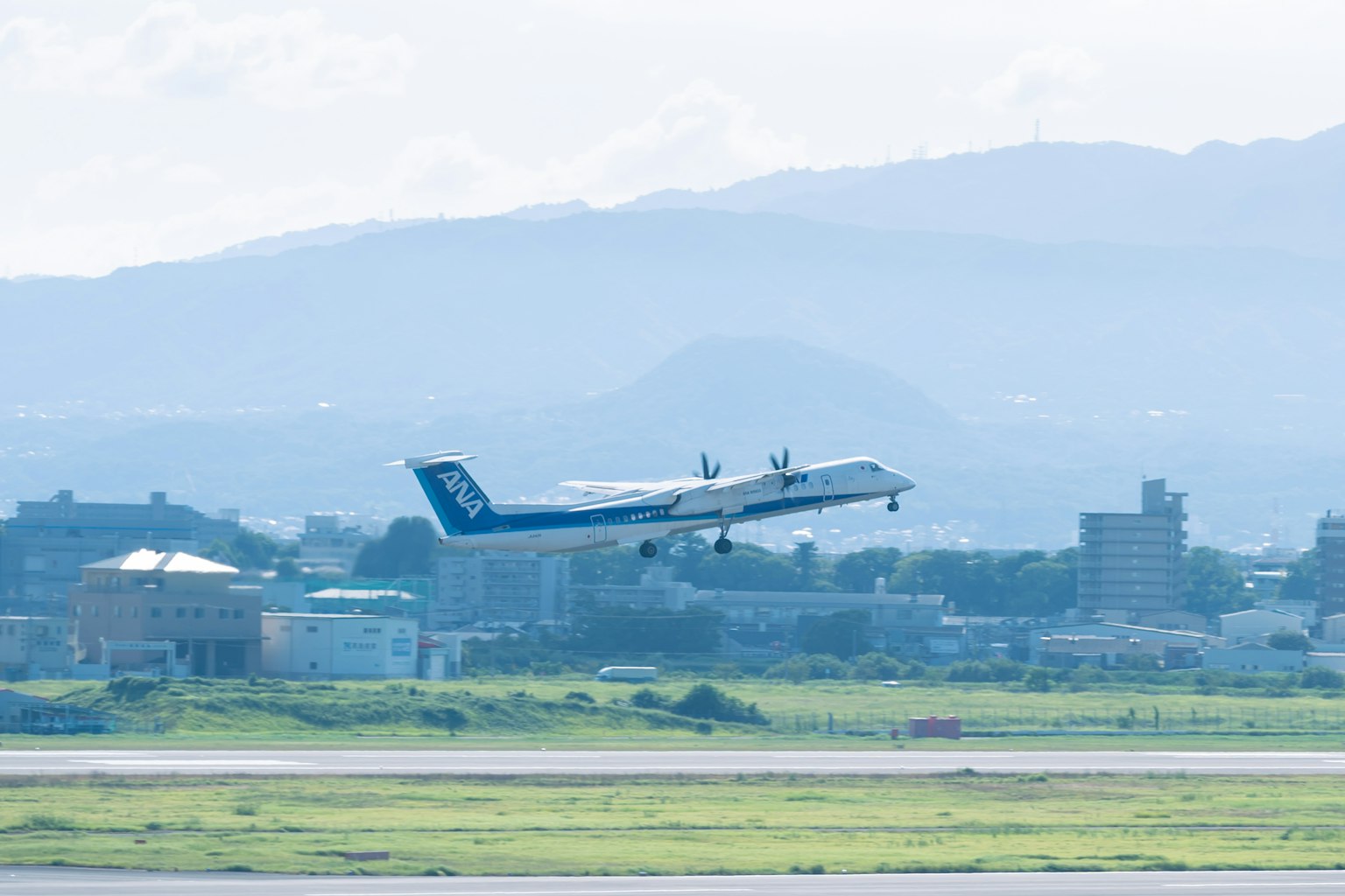Un aereo in decollo da un aeroporto con una coda blu e erba verde in primo piano