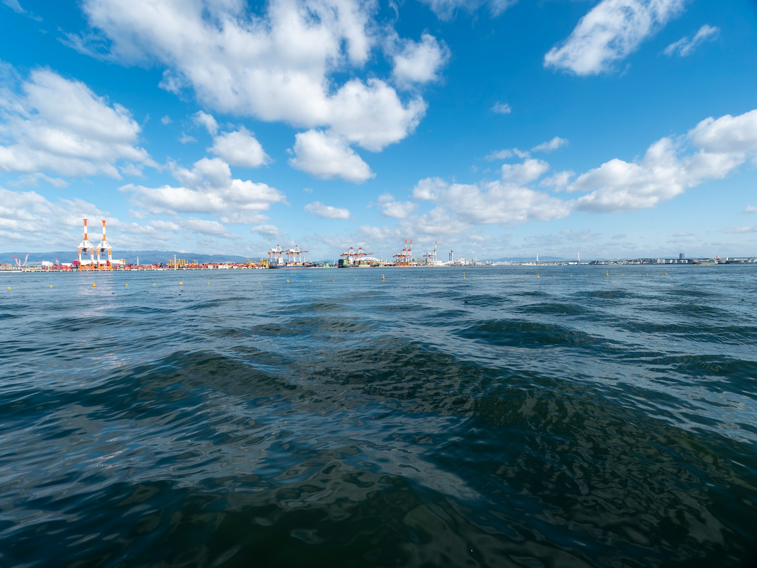 Superficie d'acqua calma che riflette il cielo blu e le nuvole bianche