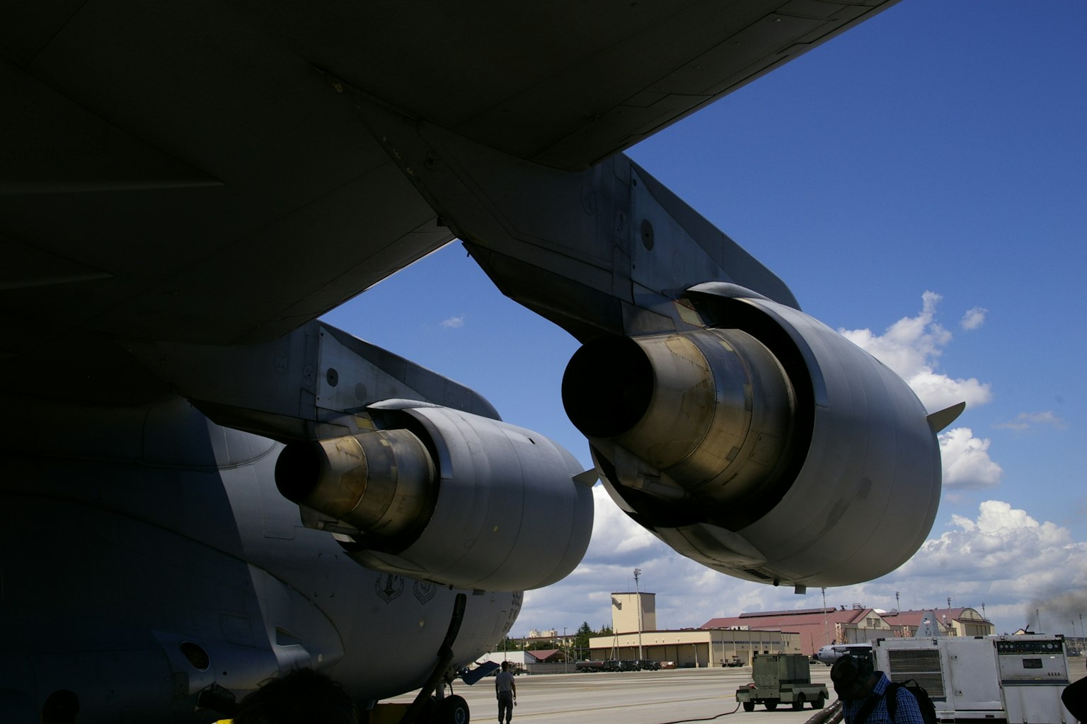 Close-up of aircraft engines with blue sky and clouds in the background