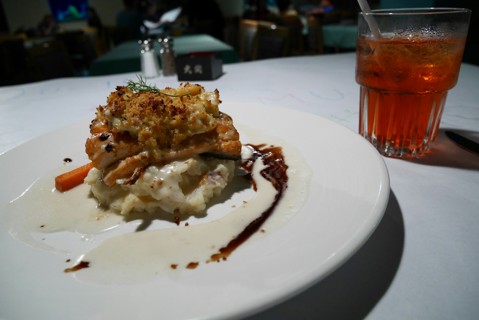 Plato de risotto cremoso cubierto con pollo a la parrilla y verduras junto a una bebida naranja brillante