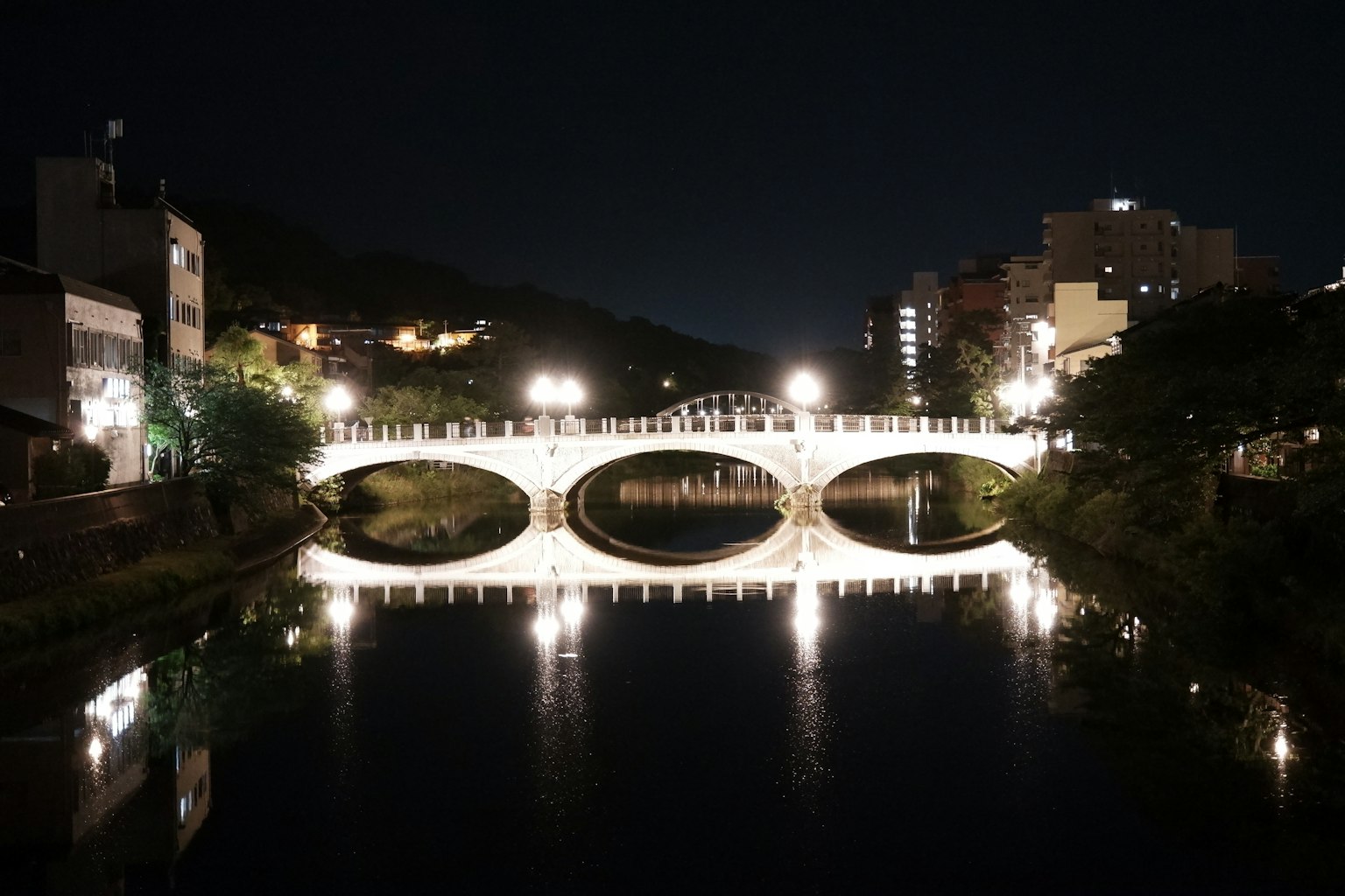 Bellissimo ponte illuminato di notte che si riflette nel fiume