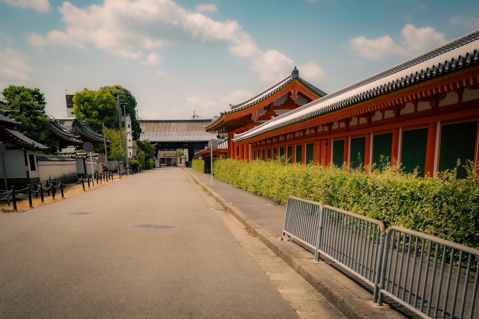 Traditional buildings along a quiet street with green hedges