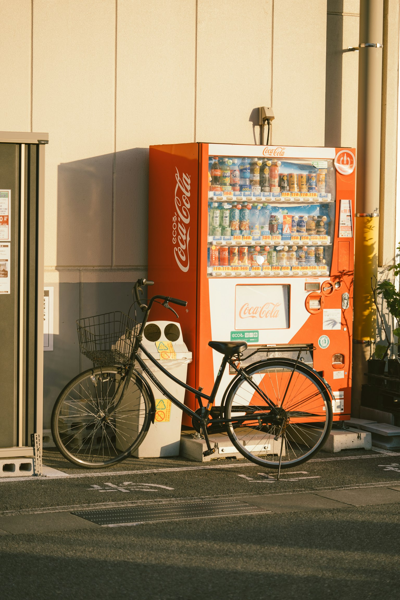 Bicicletta nera accanto a una macchina automatica Coca-Cola arancione