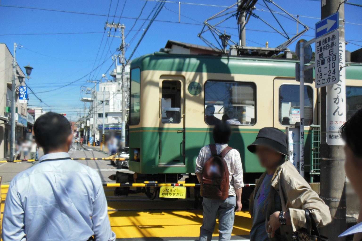 Train vert sous le ciel bleu avec des piétons à proximité