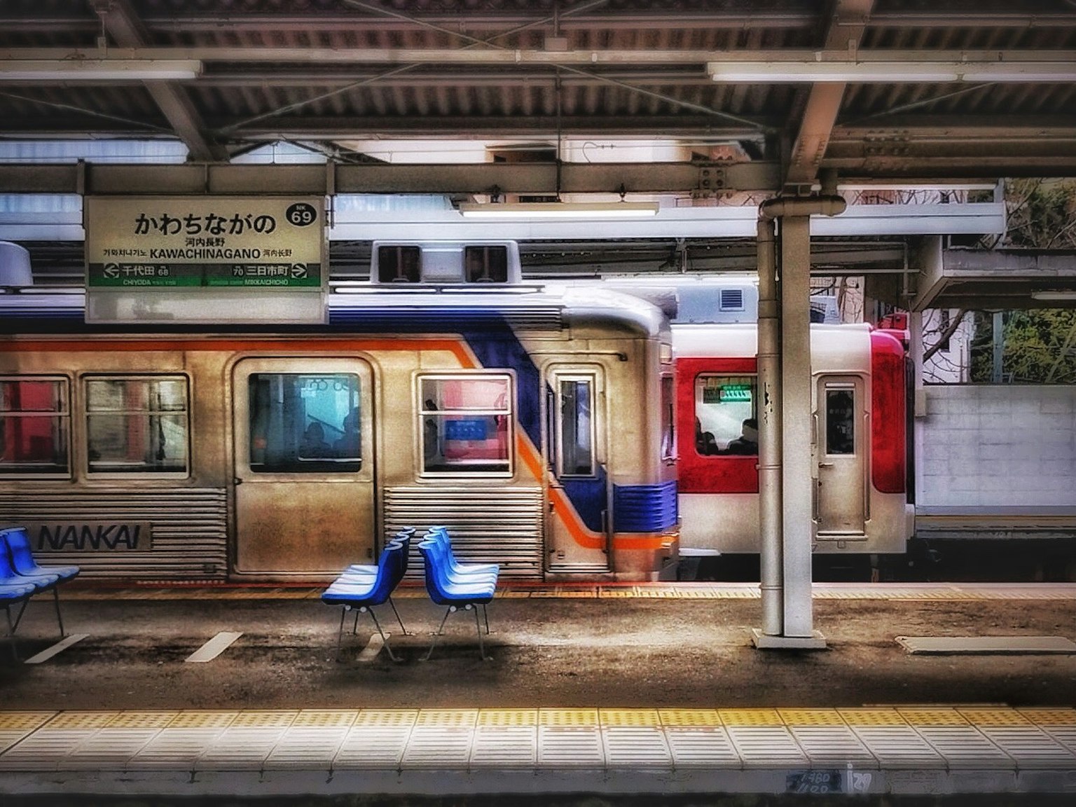 Kereta berhenti di platform stasiun dengan bangku biru
