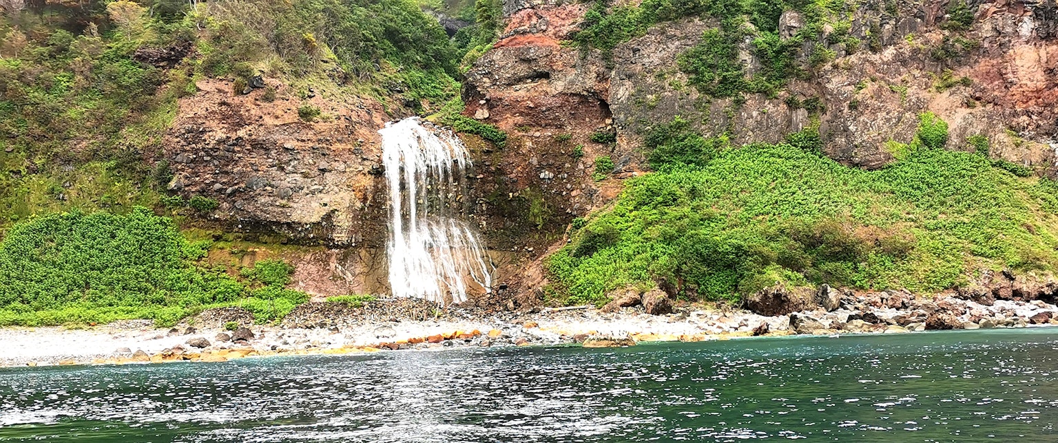 Una hermosa cascada que cae de un acantilado rocoso rodeada de vegetación