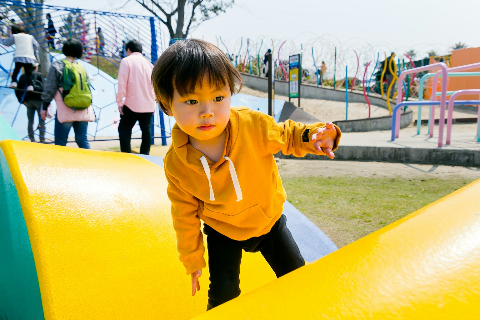 公園で遊んでいる子供　オレンジの服を着ている　滑り台の上にいる