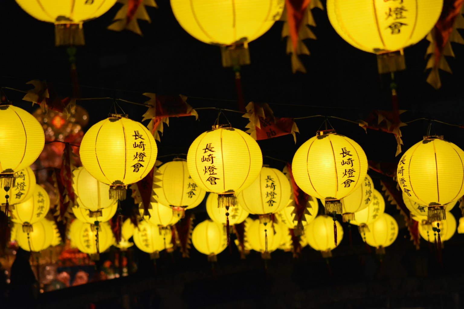 A display of yellow lanterns illuminated against a dark background