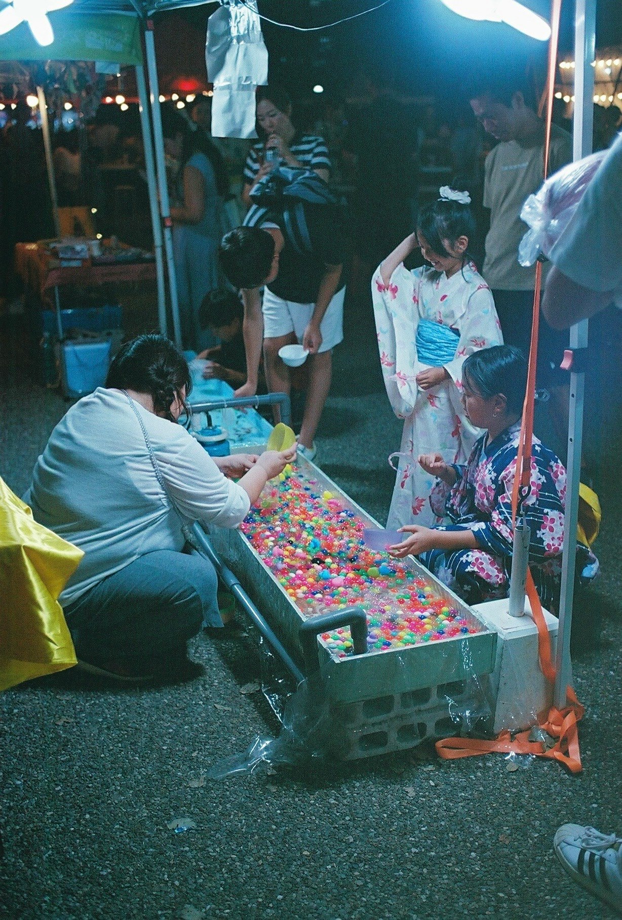 夜の屋外で子どもが遊ぶ屋台のカラフルな景品コーナー