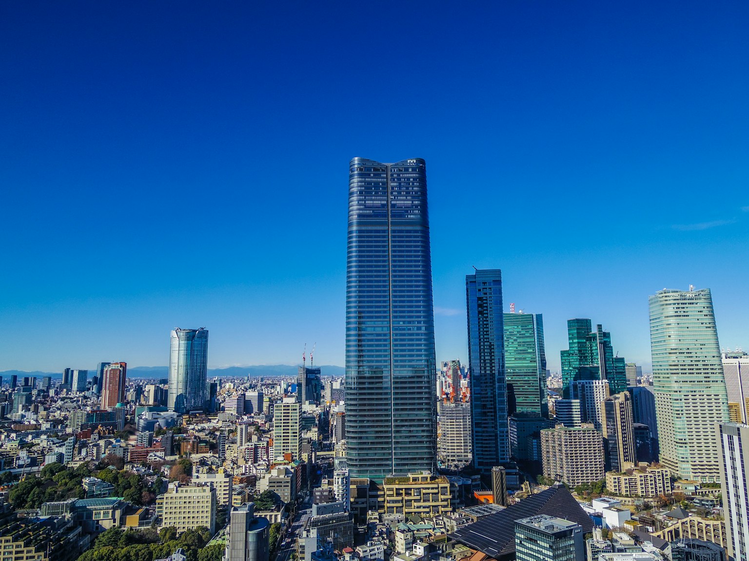 Vista aérea de los rascacielos de Tokio bajo un cielo azul claro con torres prominentes