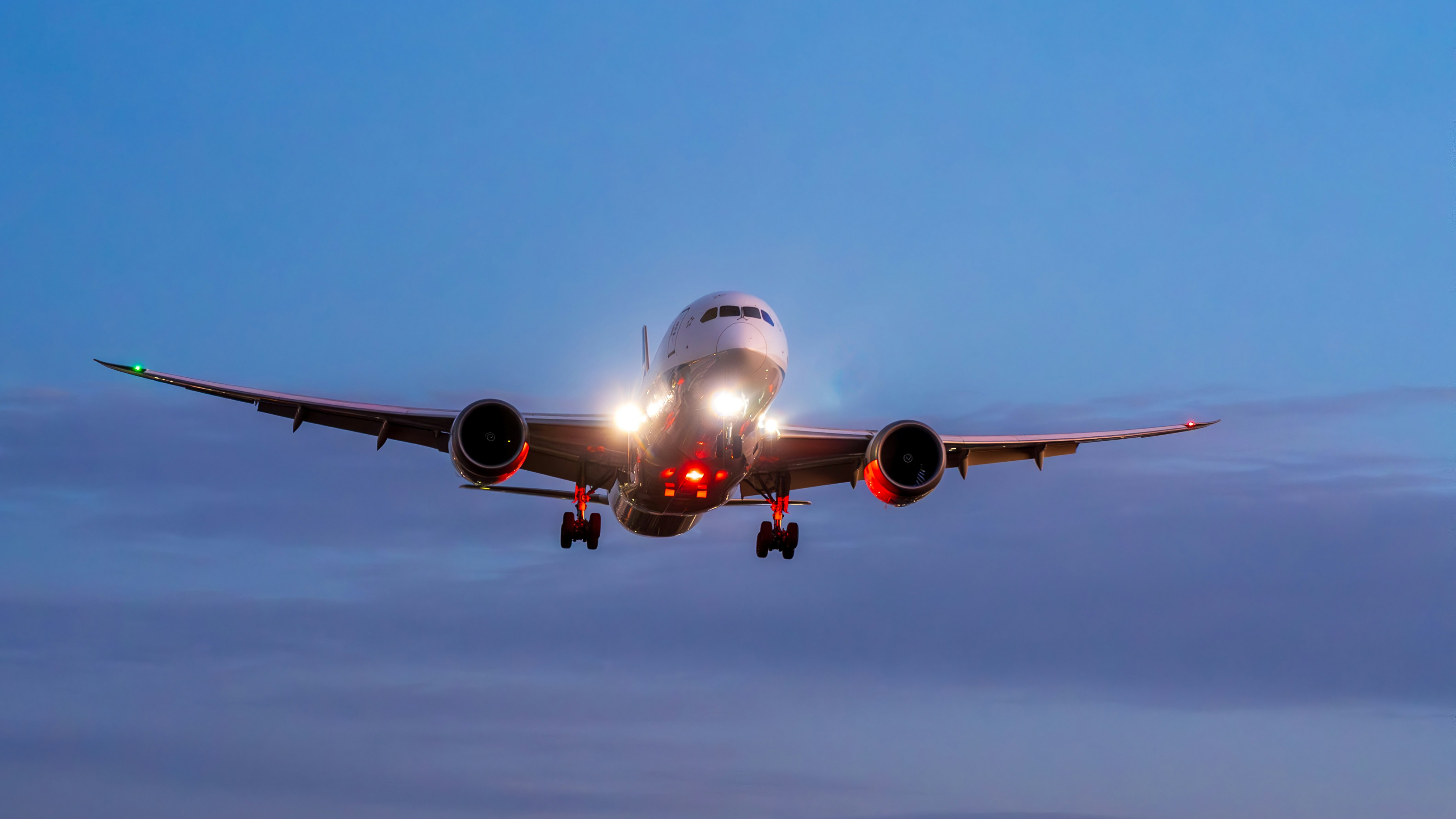 着陸態勢の旅客機が夕暮れの空に接近する様子