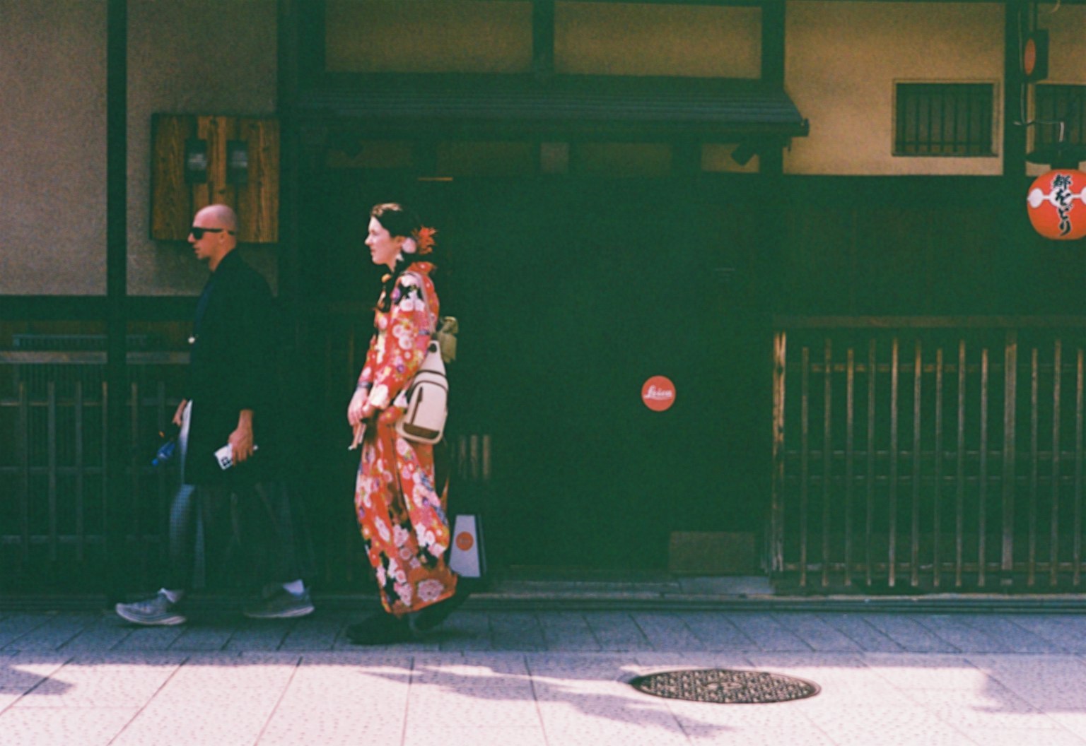 ผู้หญิงในชุดกิโมโนเดินเคียงข้างชายในชุดทันสมัยในถนนญี่ปุ่นแบบดั้งเดิม