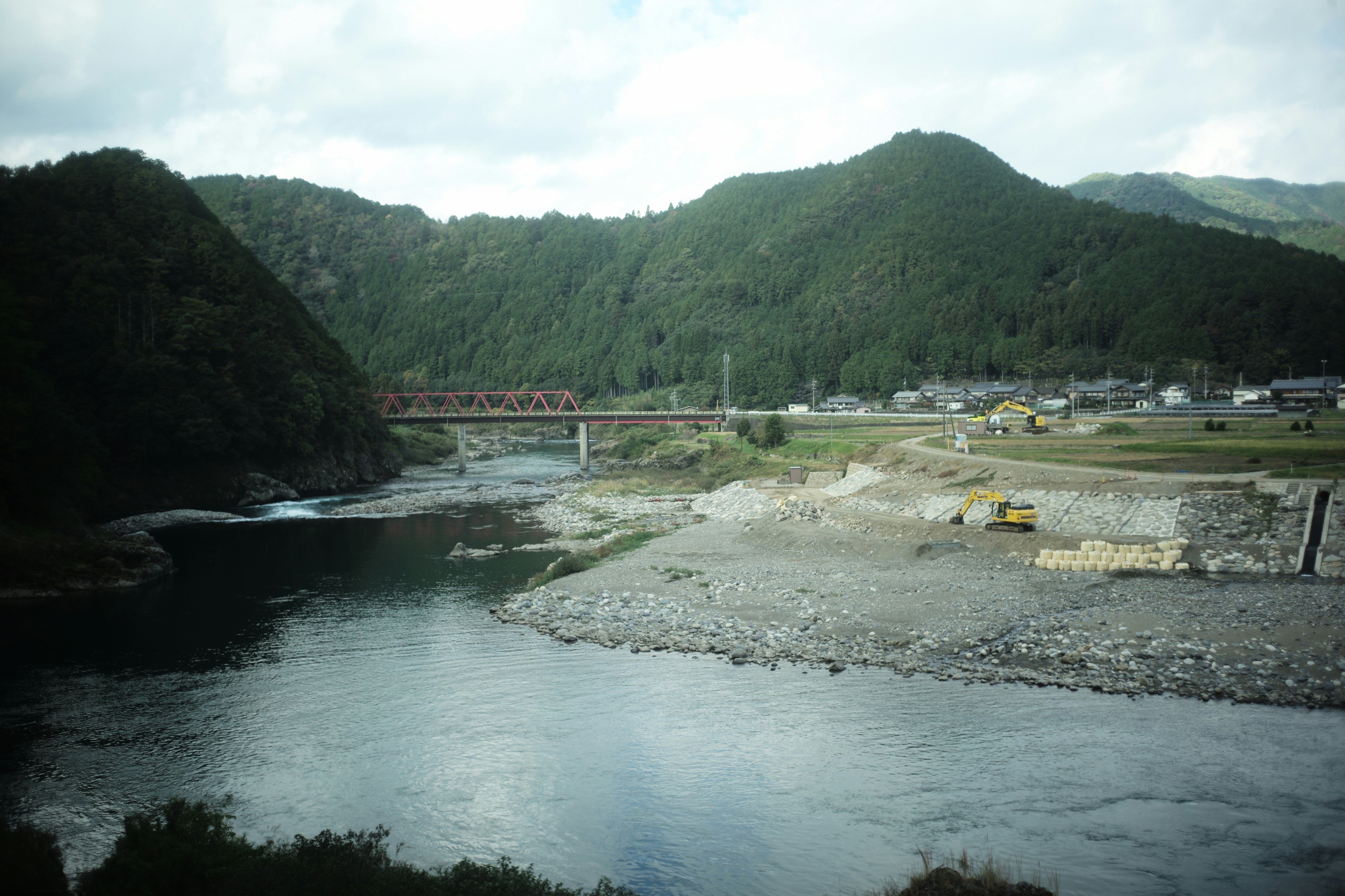 川沿いの河川敷と橋のある山あいの風景