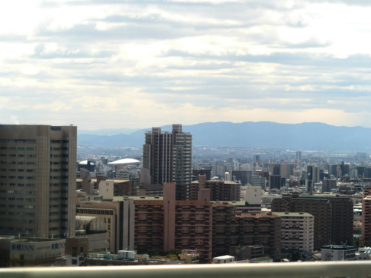 Paisaje urbano con rascacielos y montañas distantes al fondo