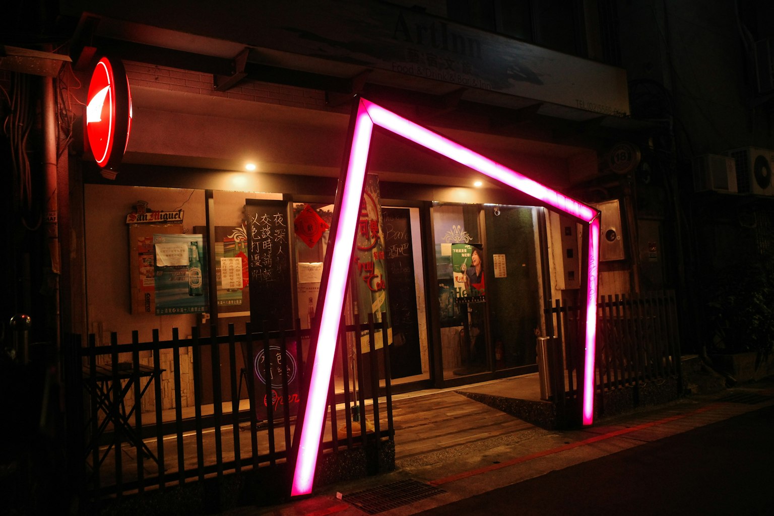 夜の街にあるカラフルなネオンの入り口が特徴的なバーの外観