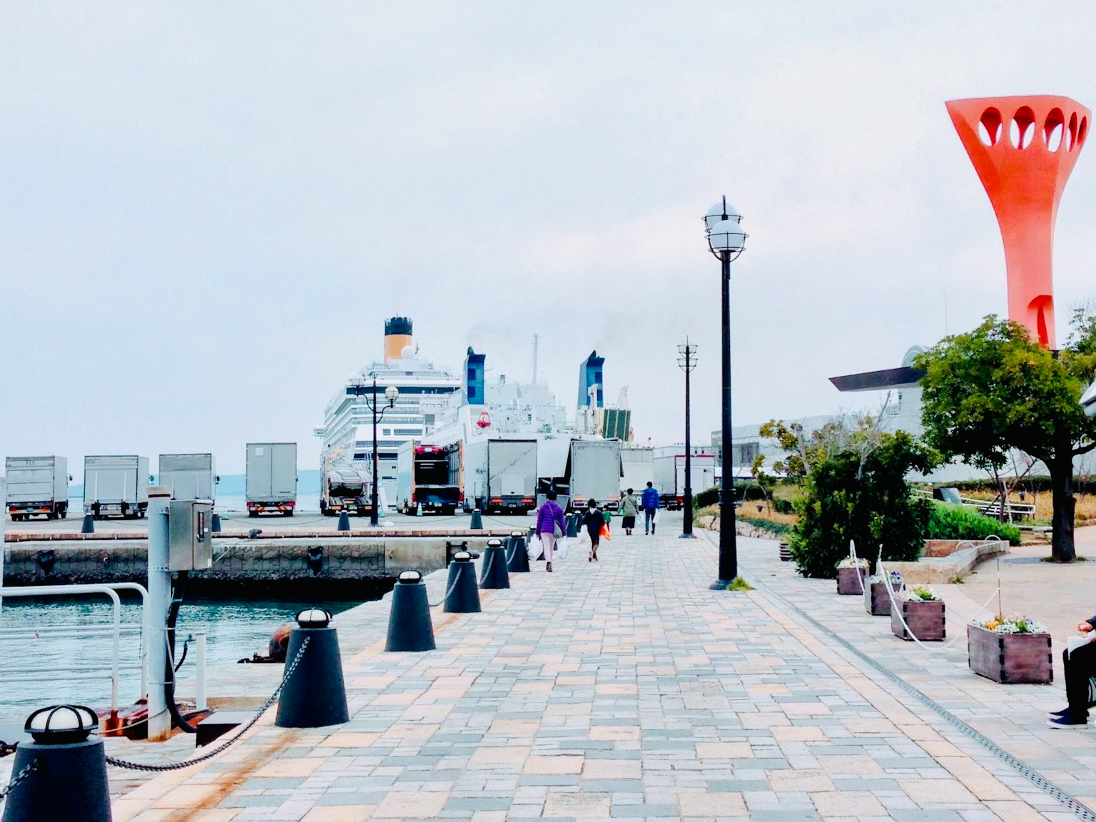 Scenic waterfront promenade featuring a cruise ship and an orange tower