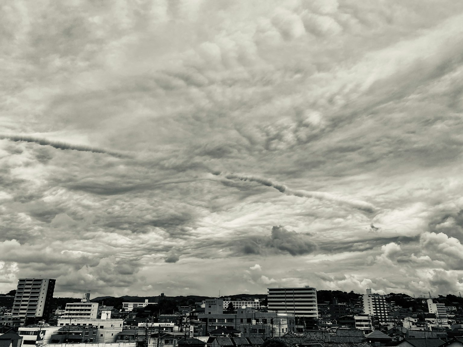 Schwarz-weiße Ansicht eines bewölkten Himmels über einer Stadtlandschaft