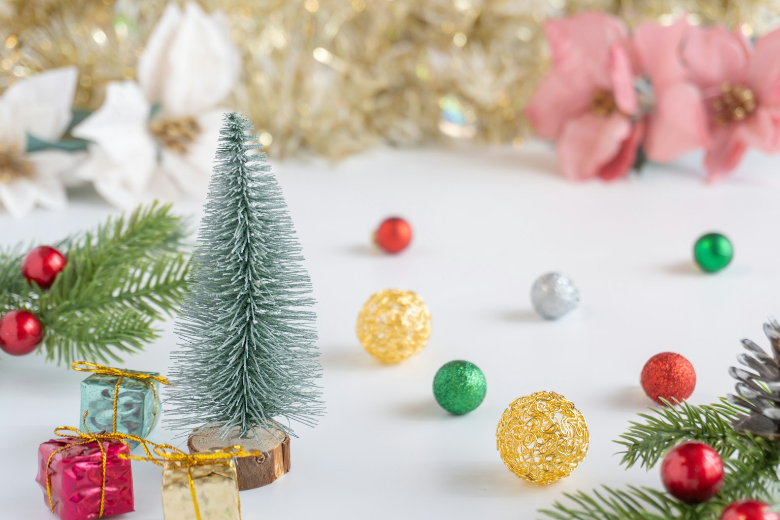 Small Christmas tree surrounded by colorful ornaments and festive decorations