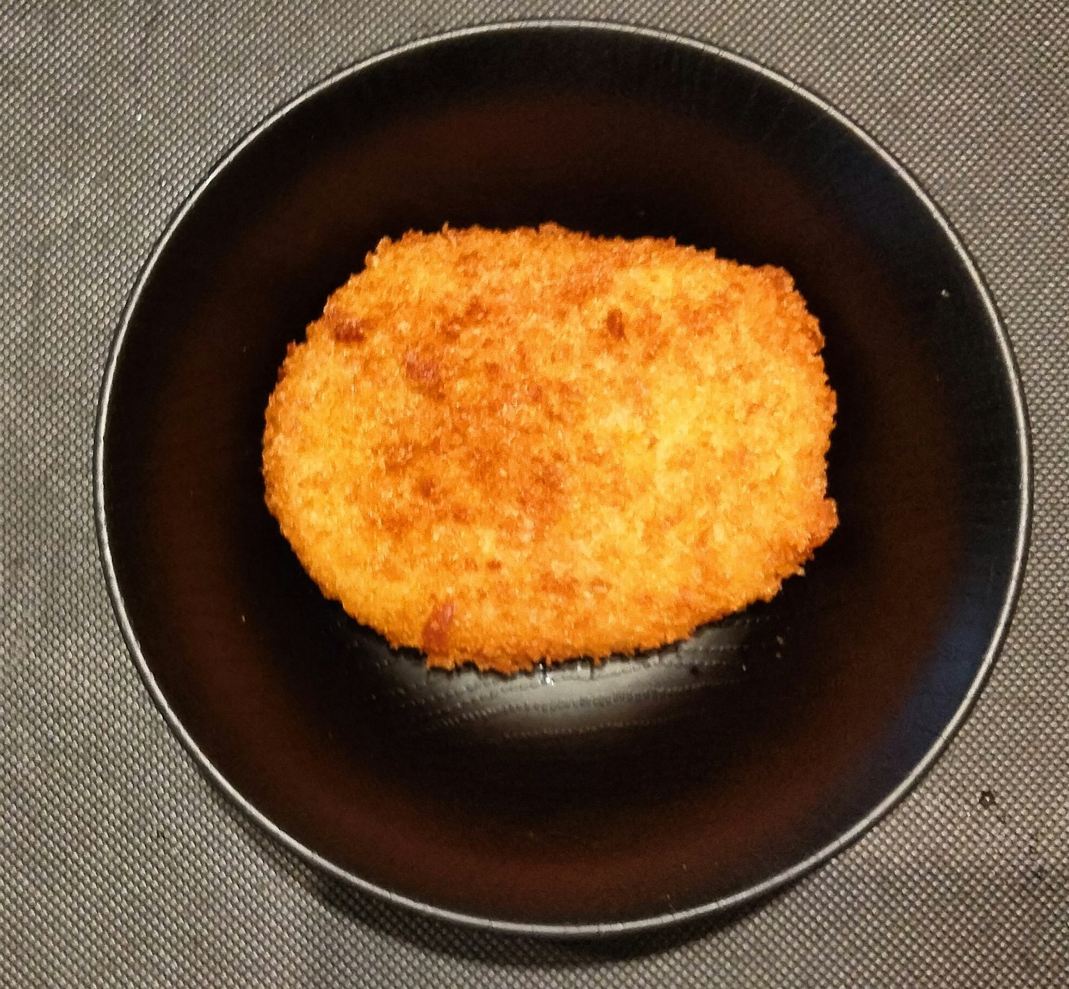 Photo of a breaded cutlet on a black plate