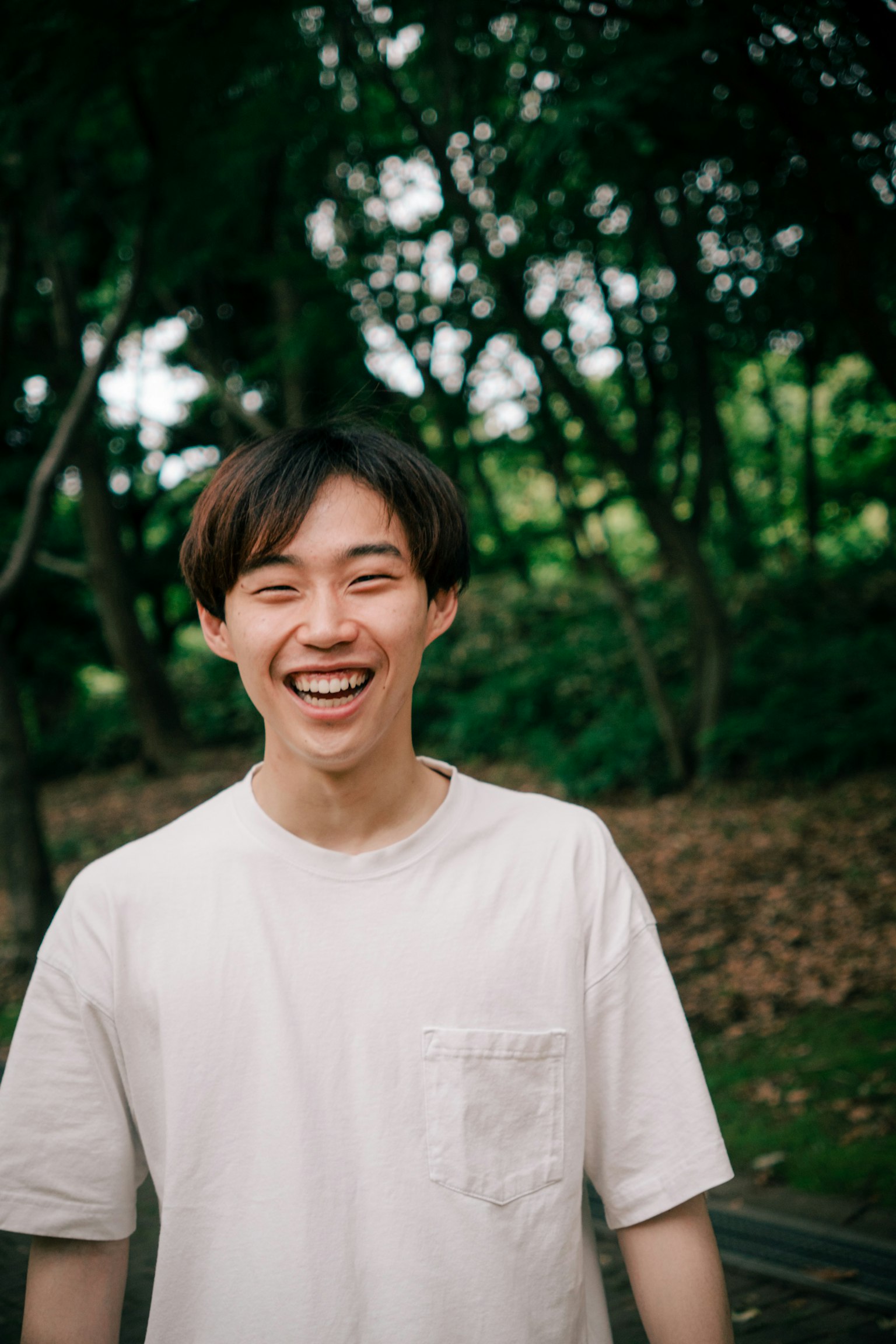年輕男性在公園中穿著白色T恤微笑