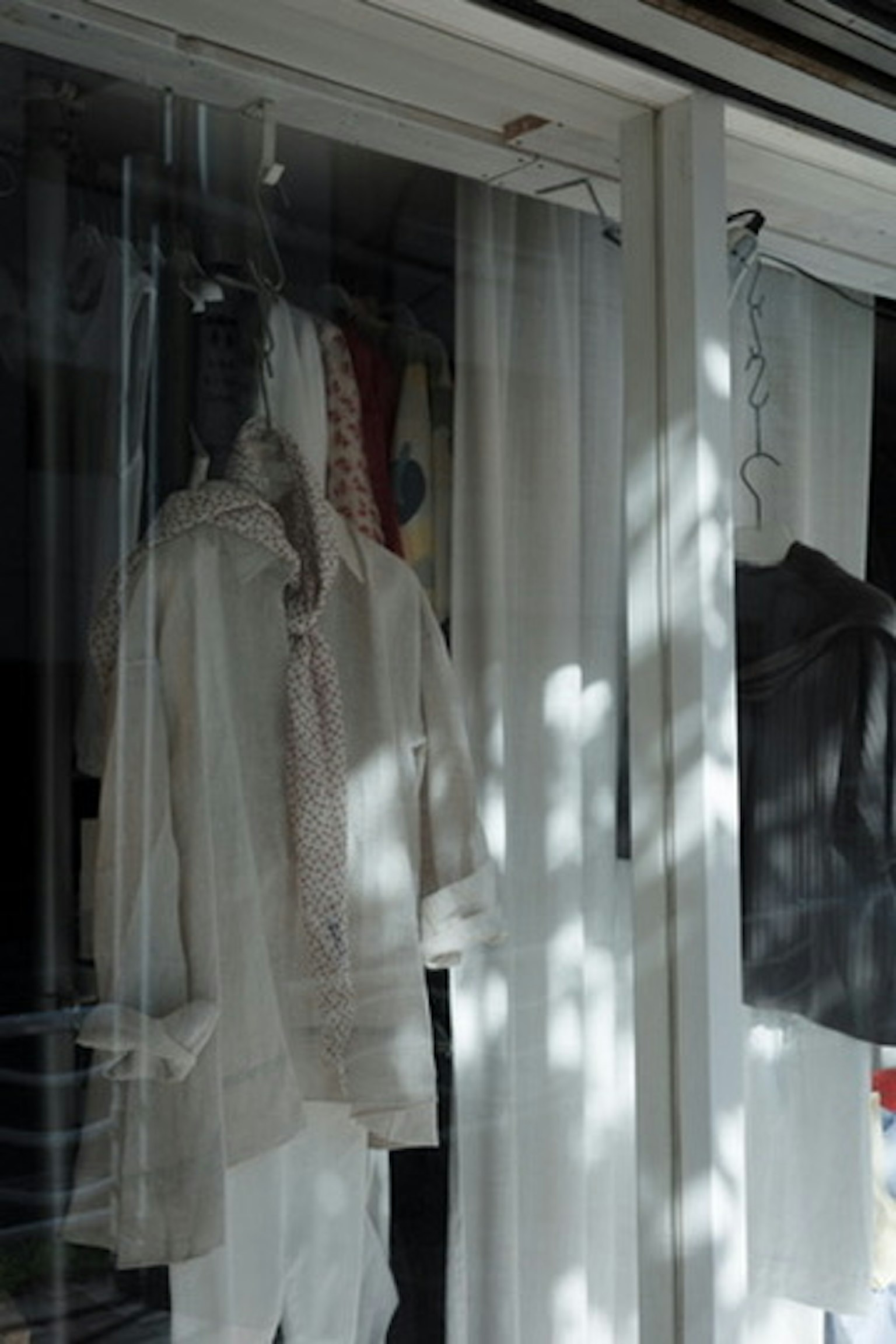 Ropa blanca y negra colgada en una ventana con hermosos reflejos de luz