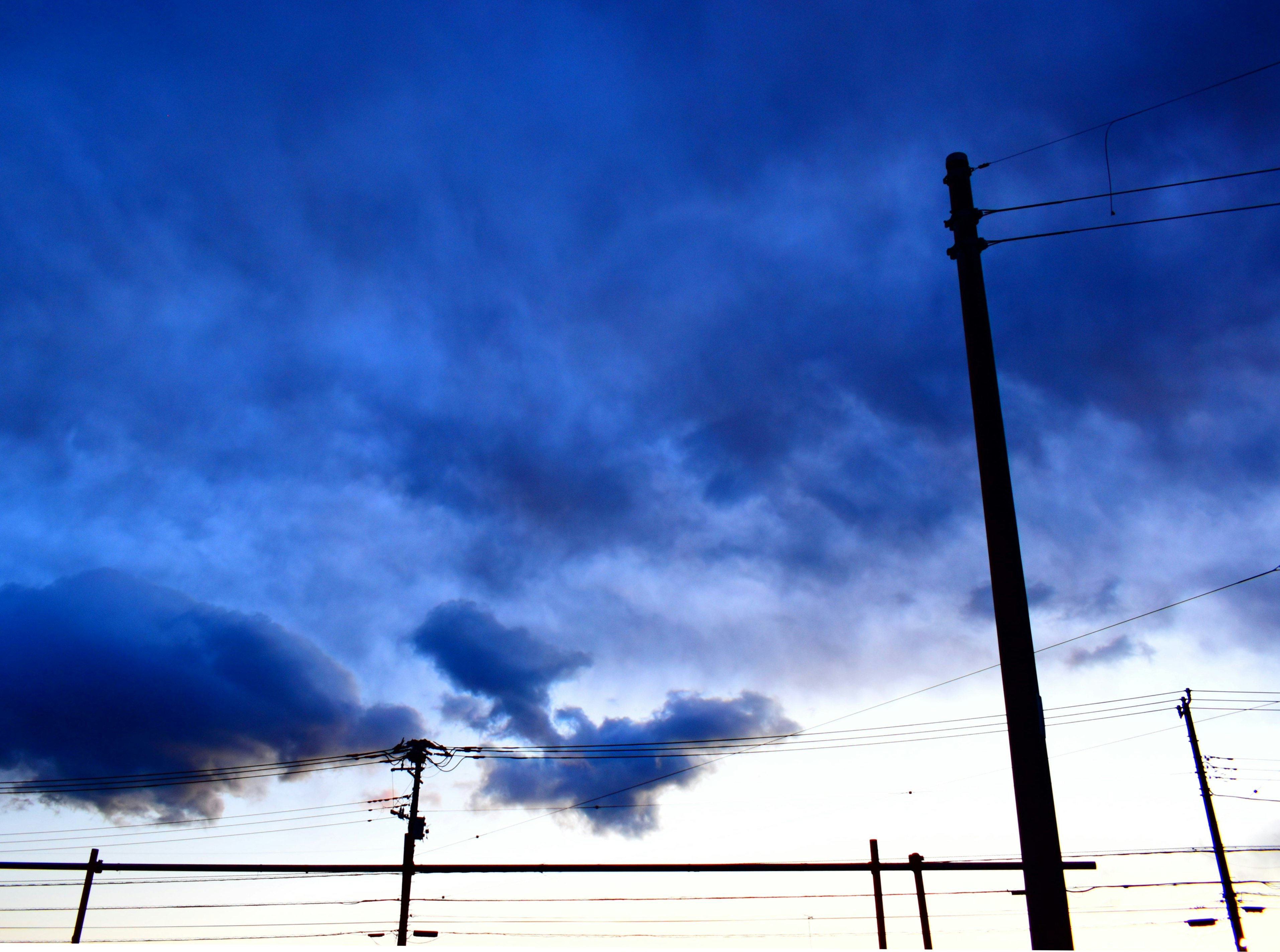 空に広がる雲と電線のシルエット