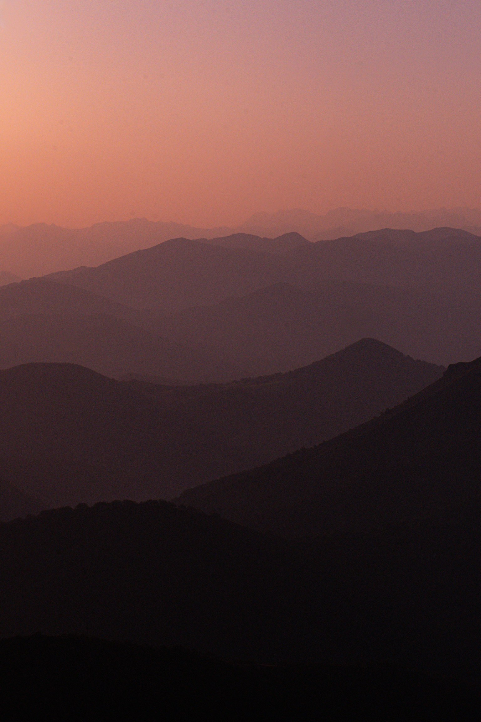 紫色の夕焼けに包まれた山々のシルエットが広がる風景