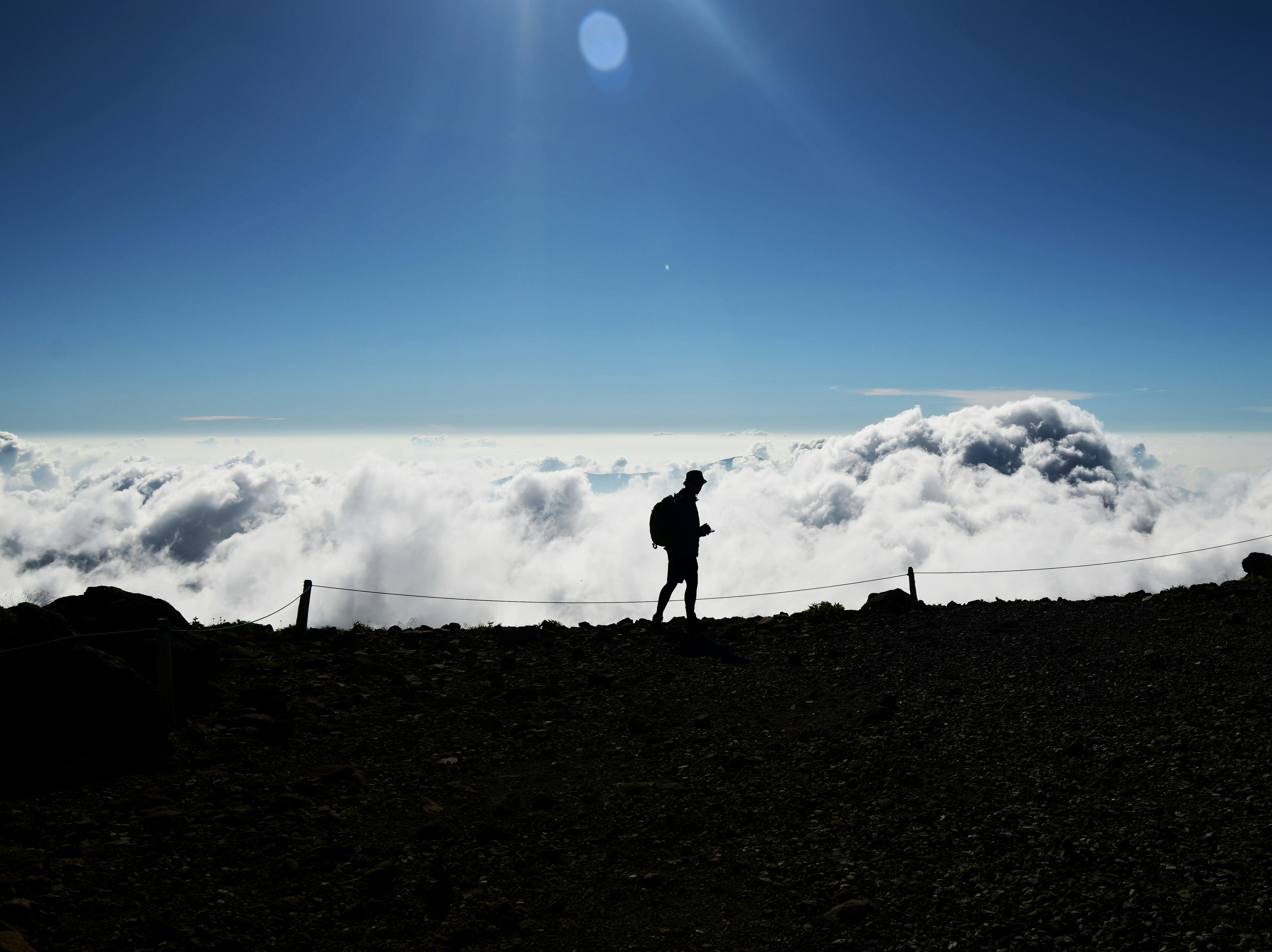 雲海の上を歩くシルエットの登山者の姿の画像